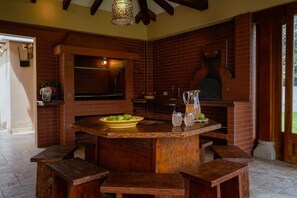 A rustic kitchen with a brick fireplace, wooden bar, and seating area. - Guayllabamba Estate - Indoor Pool, Jacuzzi & Gym (Quito)