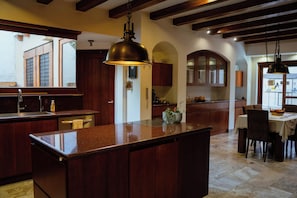 Una cocina amplia con una isla central, armarios de madera e iluminación colgante.