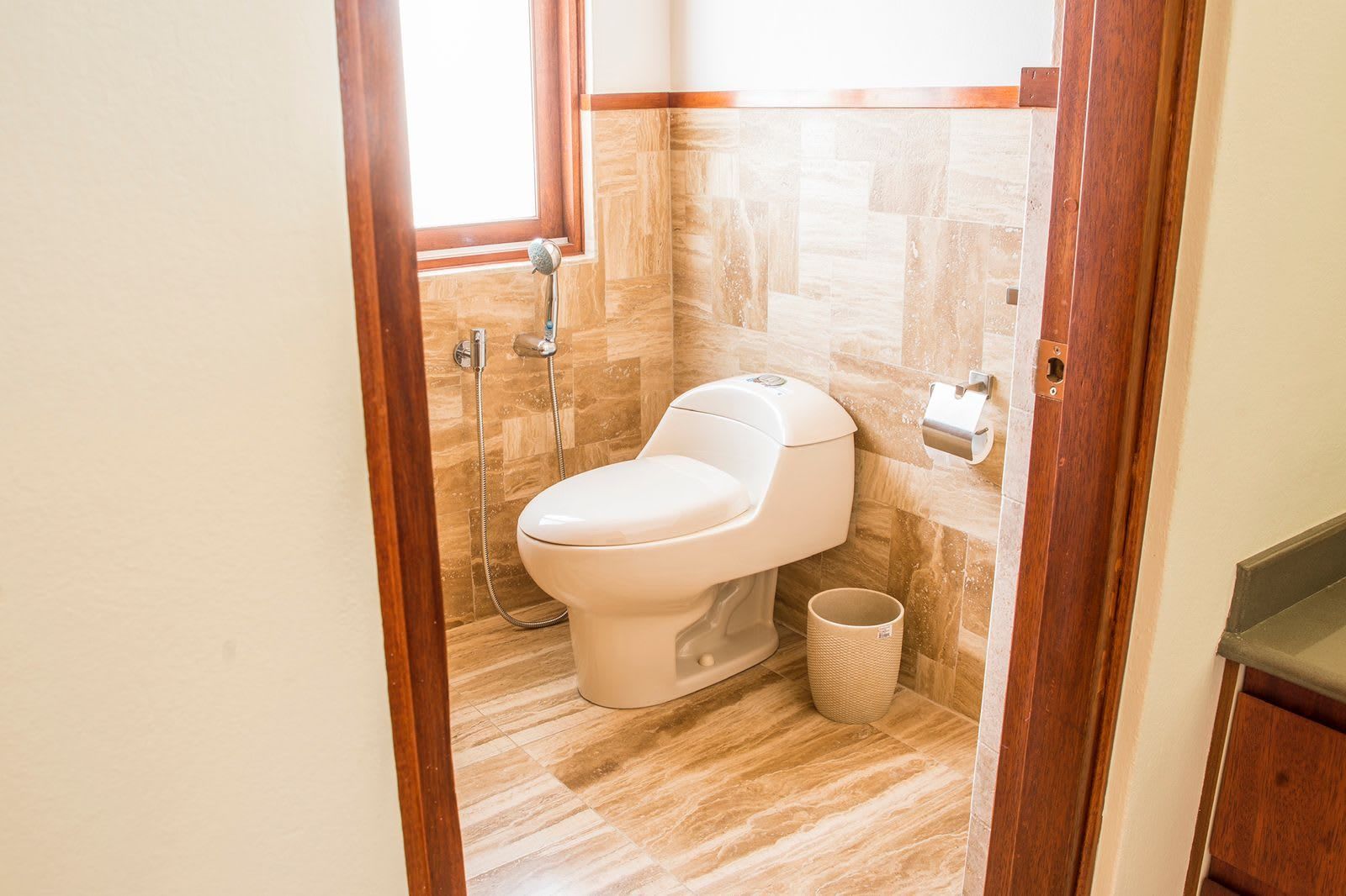 A bathroom with a toilet, a shower, and a waste bin.