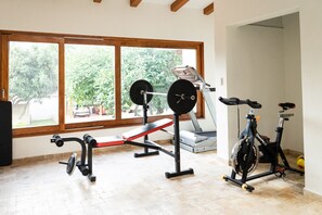 A home gym with a bench press, a stationary bike, and a treadmill.