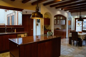 A spacious kitchen with a central island, wooden cabinets, and pendant lighting. - Guayllabamba Estate - Indoor Pool, Jacuzzi & Gym (Quito)