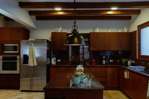 Una cocina con armarios de madera, electrodomésticos de acero inoxidable y una isla central con una lámpara colgante.