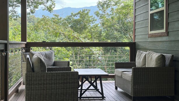 A covered outdoor seating area with wicker furniture and a view of a mountainous landscape. - Cozy cabin Peaceful Side, Townsend, TN, Laurel Valley,  no steep roads (Townsend)