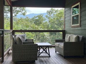 A covered outdoor seating area with wicker furniture and a view of a mountainous landscape. - Cozy cabin Peaceful Side, Townsend, TN, Laurel Valley, no steep roads (Townsend)