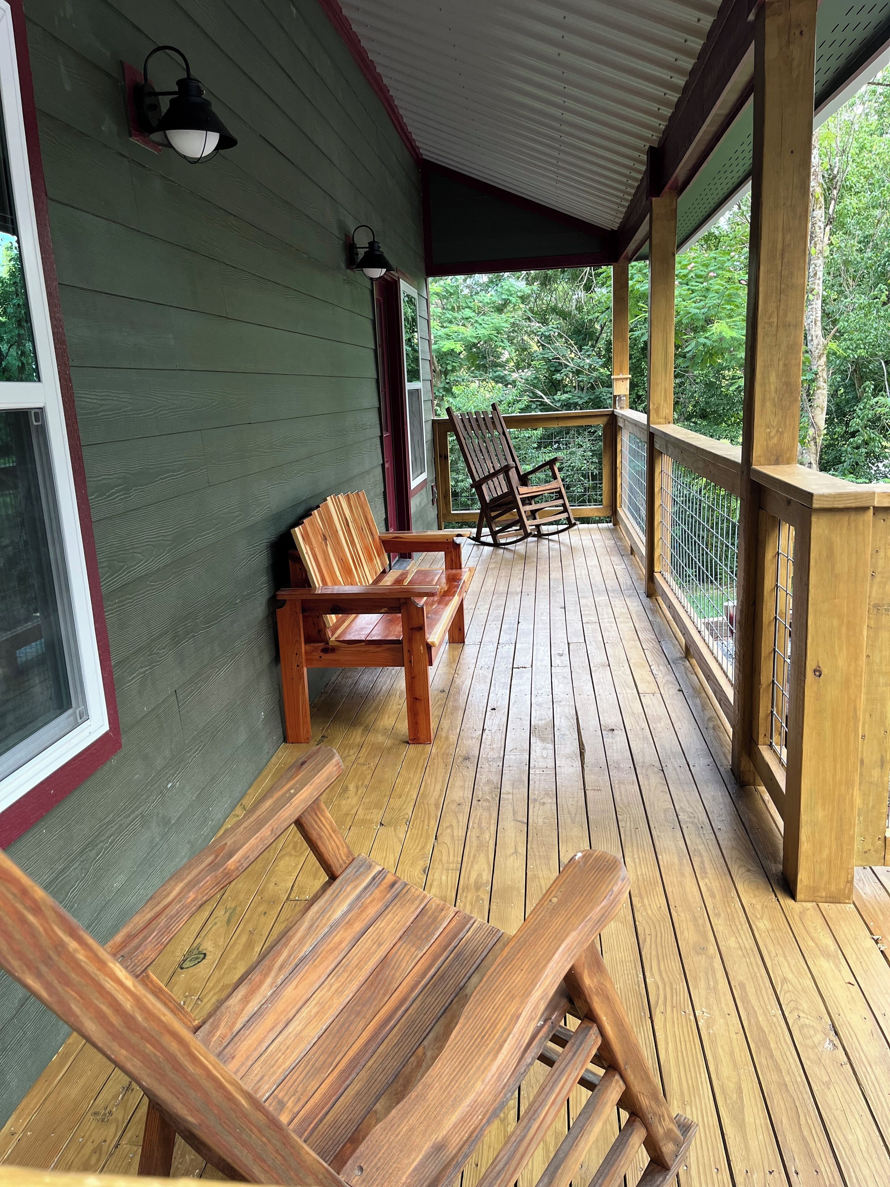 A wooden deck with benches and a rocking chair, surrounded by a metal railing.