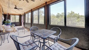A spacious patio with a wooden ceiling, large windows, and outdoor furniture.