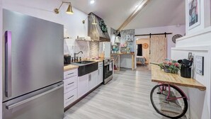 A modern kitchen with a built-in refrigerator, a stove, and a sink. There is a wooden dining table with a bicycle wheel chair.