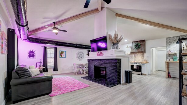 A modern living room with a fireplace, a sofa, and a dining area.
