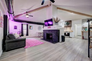 A modern living room with a fireplace, a sofa, and a dining area.