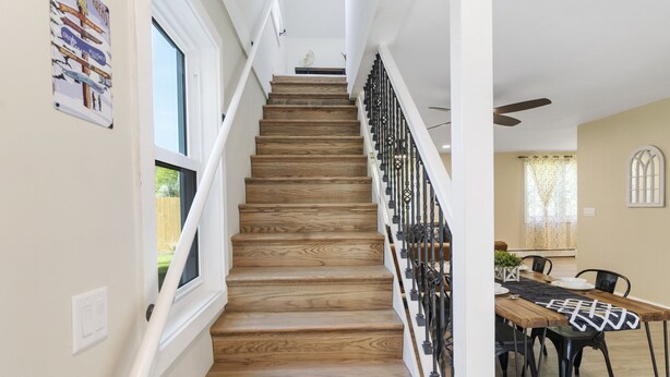 A wooden staircase with a black railing leading to a room with a dining table and chairs. - Fantastic retreat 5 mins from Village with media room, AC and sauna! (Stowe)