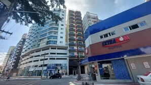 Un immeuble à plusieurs étages dont le rez-de-chaussée est occupé par des commerces, notamment un magasin appelé « EXTRABOM express ».