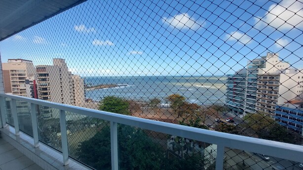 Un balcon avec vue sur l’océan et les bâtiments.