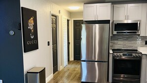 A modern kitchen with stainless steel appliances, a microwave, and a tiled backsplash.