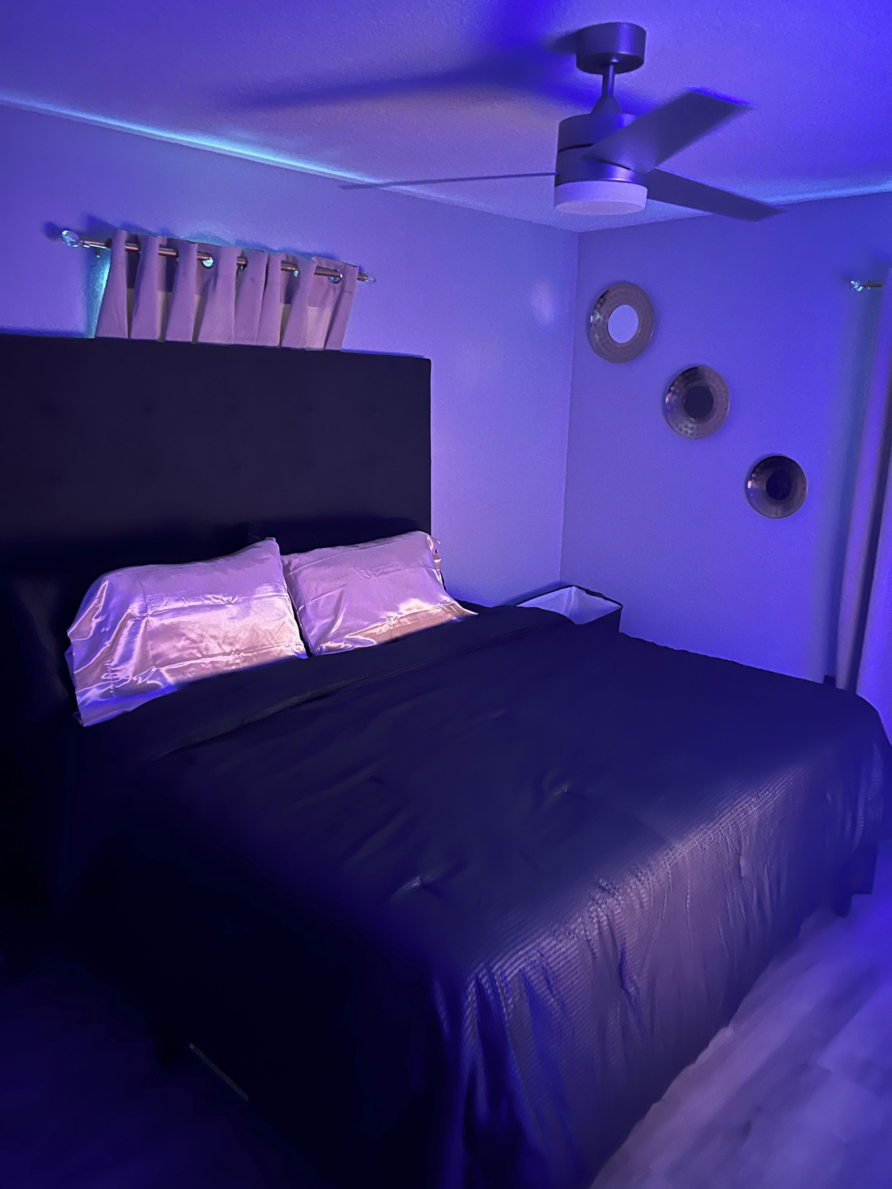 A bedroom with a bed, a ceiling fan, and wall-mounted circular decorations.