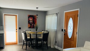 A living room with a dining area, a sofa, a ceiling fan, and a door with a window.