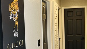 A hallway with a black wall featuring a tiger logo and the word "GUCCI".