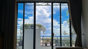 A room with a sliding glass door leading to a balcony with a view of the sky and mountains. - Elysinam Boutique Hotel (Bai Chay)