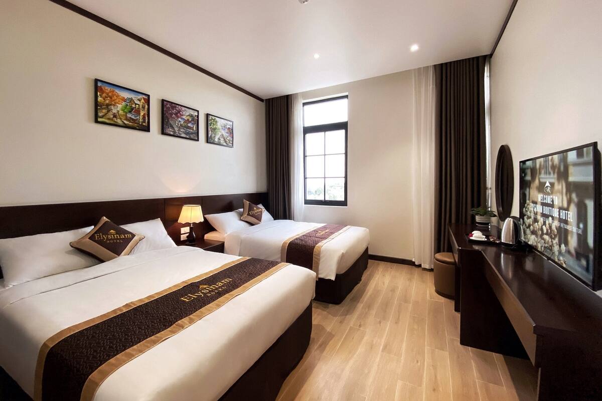 Quarto de hotel com duas camas, televisão e janela.