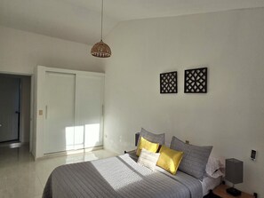 Ein Schlafzimmer mit einem Bett, einer Pendelleuchte, einer Tür und zwei Wandpaneelen.