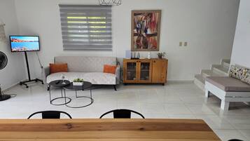 A living room with a sofa, a coffee table, a TV, a cabinet, and a staircase.