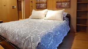 Ein Schlafzimmer mit einem großen Bett, zwei Bildern an der Wand und einem Holzschrank.