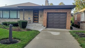 Ein Wohnhaus mit Ziegelverkleidung, einer Garage und einem gepflegten Rasen.