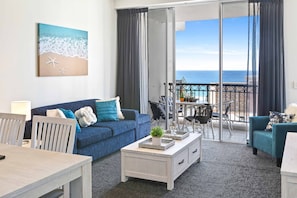 Relax in this stylish living room with a sofa, coffee table, and dining area, offering a balcony with a breathtaking ocean view.