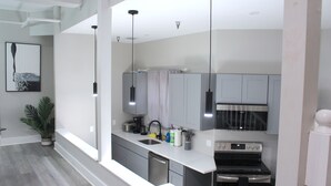 Una cocina moderna con armarios grises, un lavamanos de acero inoxidable y un horno empotrado.