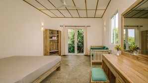 A room with a bed, a wooden bench, a desk, a chair, a wardrobe, and a sliding glass door leading to a balcony. - Jungle Beach Ahungalla - Classic Room (Ahungalla)