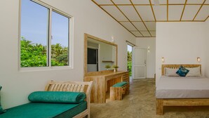 A bedroom with a bed, a wooden desk, a chair, a bench, a large mirror, and a view of greenery outside. - Jungle Beach Ahungalla - Classic Room (Ahungalla)