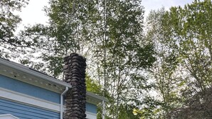 A blue house with a stone chimney, surrounded by lush greenery and flowering plants. - Catskill dreamy pet friendly country house  for a unique getaway experience. (Claryville)