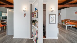 A modern interior with a wooden ceiling, white walls, and a bookshelf with books and decorative items. - NEW Steps to Beach, Prime City Center, Firepit, Hot Tub, PS5, Pet Friendly (Rockaway Beach)