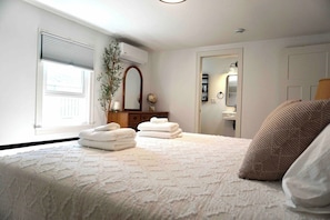 Une chambre à coucher avec un lit, une commode, un miroir et une fenêtre.