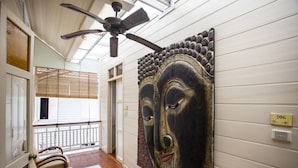A hallway with a ceiling fan, a large wall-mounted artwork, a wooden bench, and a door with a number plate. - Baan Dinso (Bangkok)