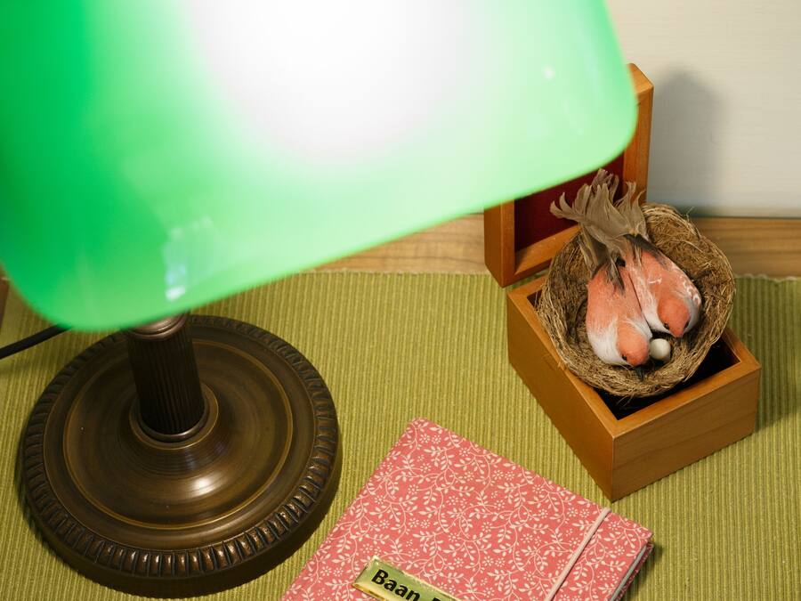 Una lámpara de escritorio, un cuaderno y una pequeña caja de madera con una figurita de pájaro.