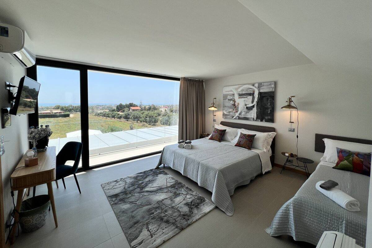 Ein modernes Hotelzimmer mit zwei Betten, einem Schreibtisch und einem großen Fenster mit schöner Aussicht.
