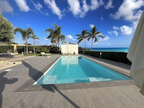 A rectangular swimming pool with a clear blue water surface, surrounded by a paved deck.