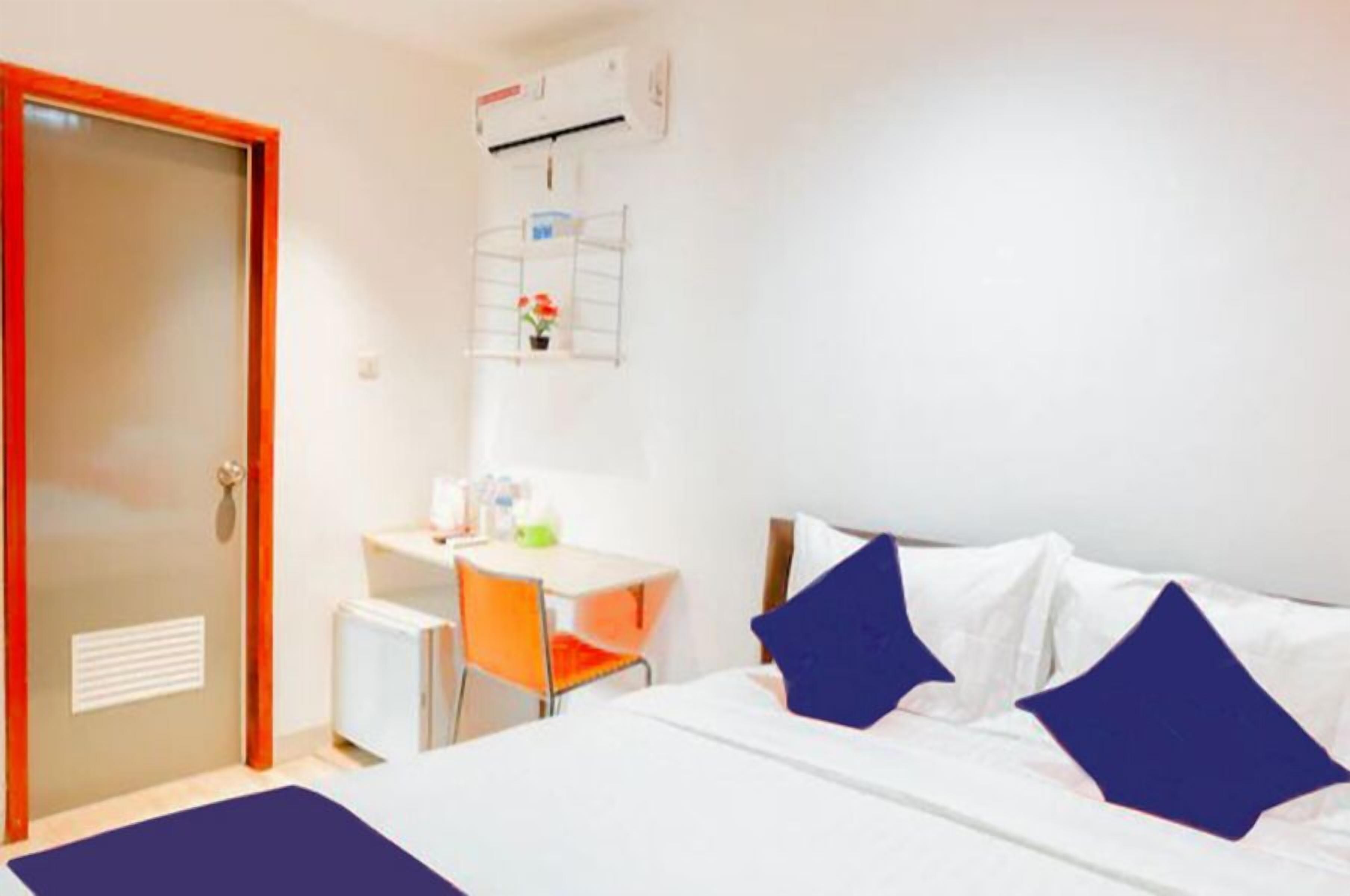 Habitación de hotel con cama, escritorio, silla, radiador y aire acondicionado.