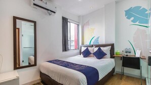 Habitación de hotel con cama, escritorio, silla, espejo y ventana.