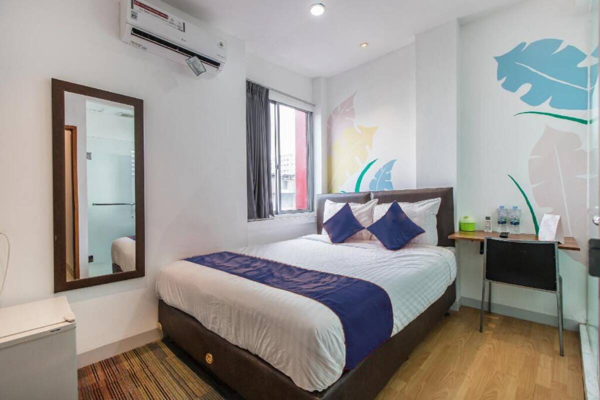 Een hotelkamer met een bed, een bureau, een stoel, een spiegel en een raam.