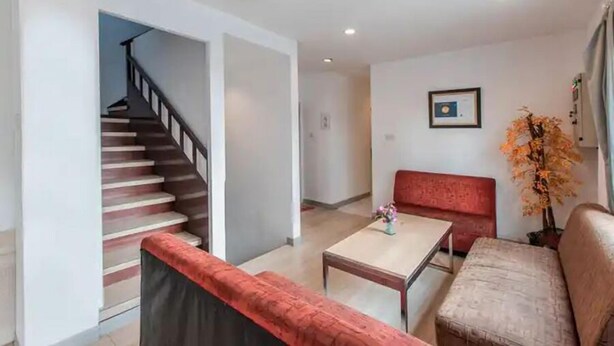 Una sala de estar moderna con una escalera, un sofá rojo, una mesa de centro y un certificado enmarcado en la pared.