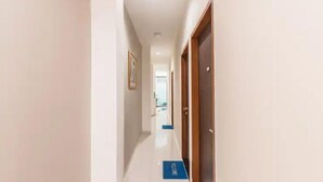 Un pasillo de hotel con un indicador azul en el suelo, una puerta de madera y un cuadro en la pared.