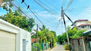 A narrow street lined with residential buildings, power lines overhead, and a few birds flying. - Sea Breeze (Negombo)