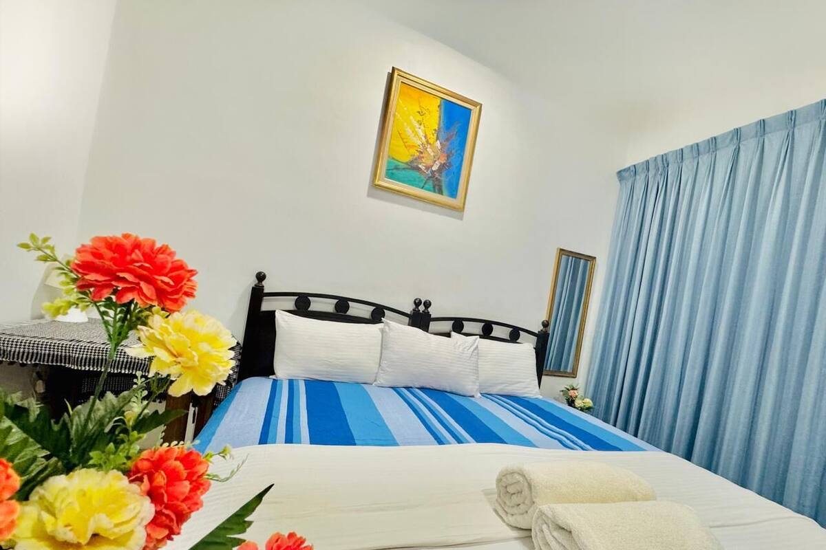 Une chambre d’hôtel avec un lit, un tableau au mur et une fenêtre avec des rideaux.