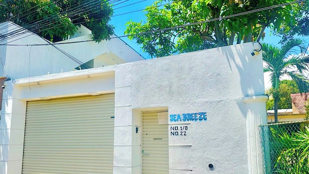 A building with a closed garage door and a sign reading "SEA BREEZE NO.1/8 NO.22". - Sea Breeze (Negombo)