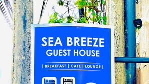 A sign for Sea Breeze Guest House offering breakfast, cafe, lounge, private rooms, dormitory rooms, free wifi, and F&B. It also advertises over-night hostel services at Browns Beach with contact details. - Sea Breeze (Negombo)