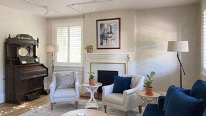 Una sala de estar con chimenea, dos sillones, un sofá, una mesa de centro y un piano de cola.