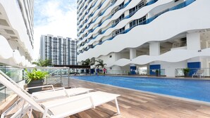 A poolside area with lounge chairs and a swimming pool, surrounded by modern buildings. - The Wave Residence By I Housing (Malacca City)