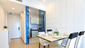 A modern kitchen with white cabinets, a countertop, and a sink. There is a dining area with a table and chairs. - The Wave Residence By I Housing (Malacca City)