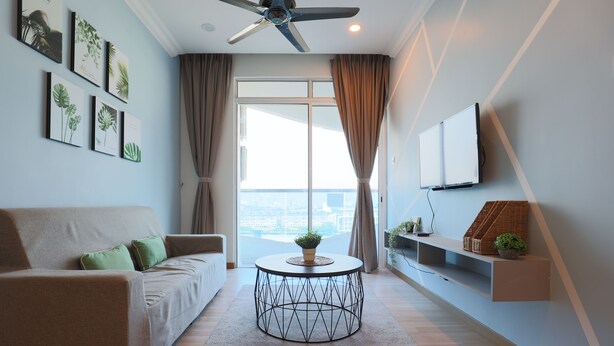 A modern living room with a sofa, a round coffee table, and a TV mounted on the wall. - The Wave Residence By I Housing (Malacca City)